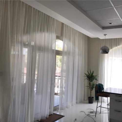 Light blue-green sheer curtains pulled back to reveal a window in a modern living space